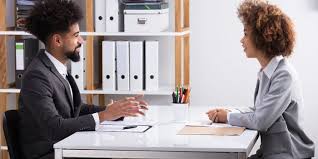 Two people sitting at a table talking to each other.