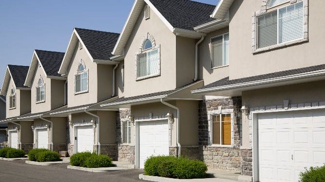 A row of three story houses with garage doors.