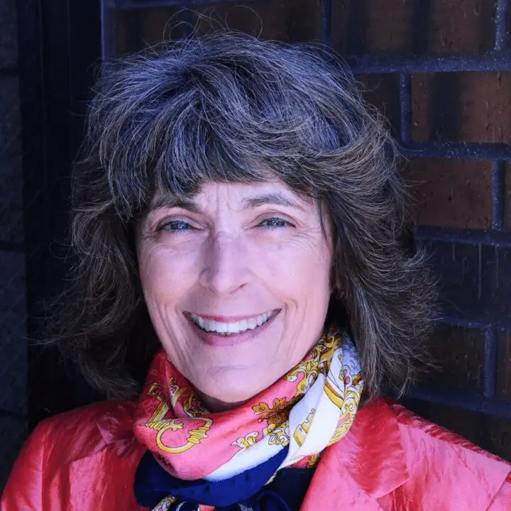 A woman with grey hair wearing a red jacket.