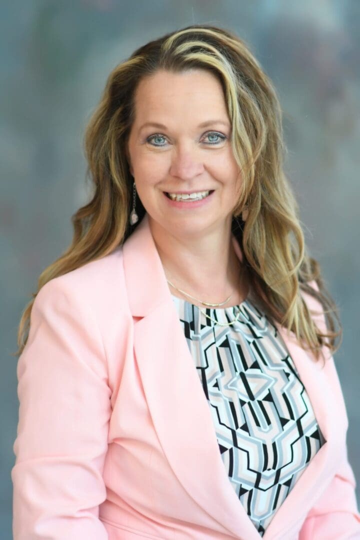 A woman in a pink jacket and black and white dress.