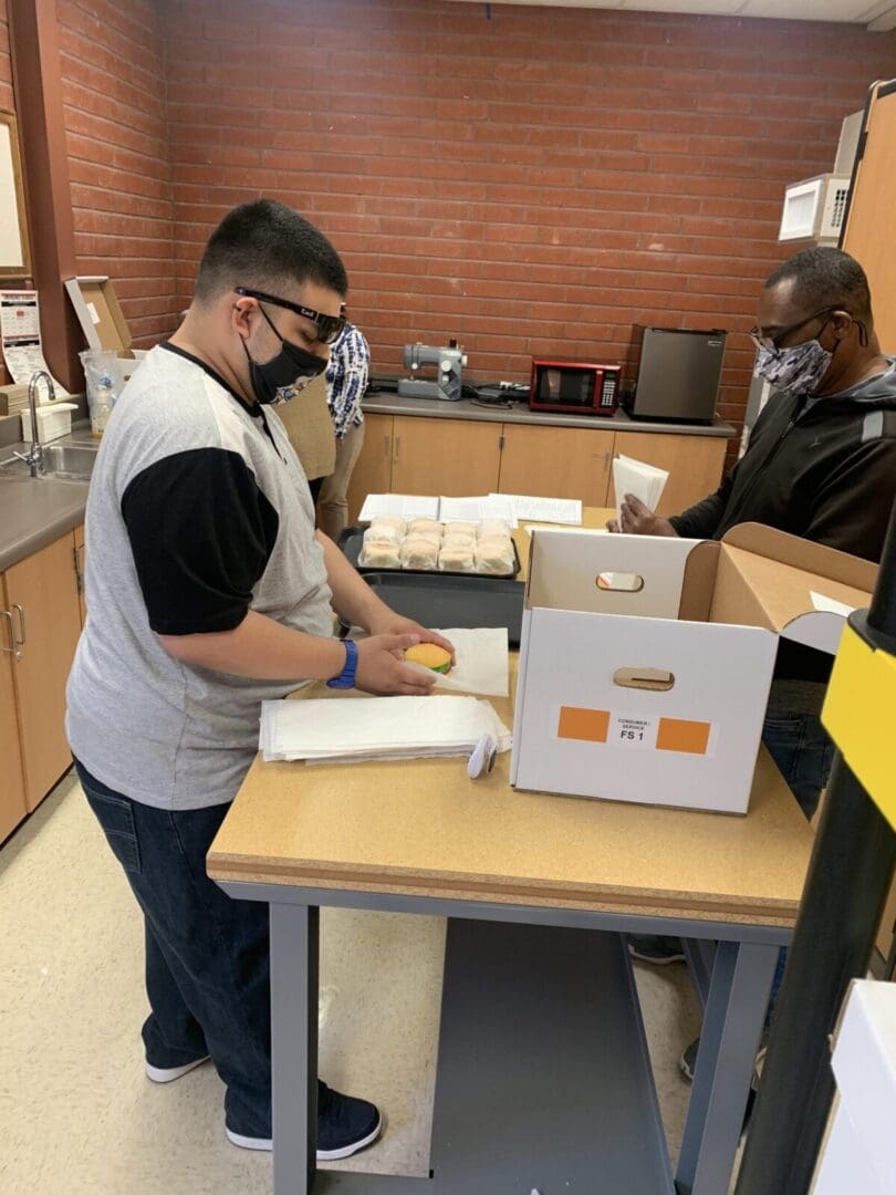 Masked worker wrapping sandwiches at counter