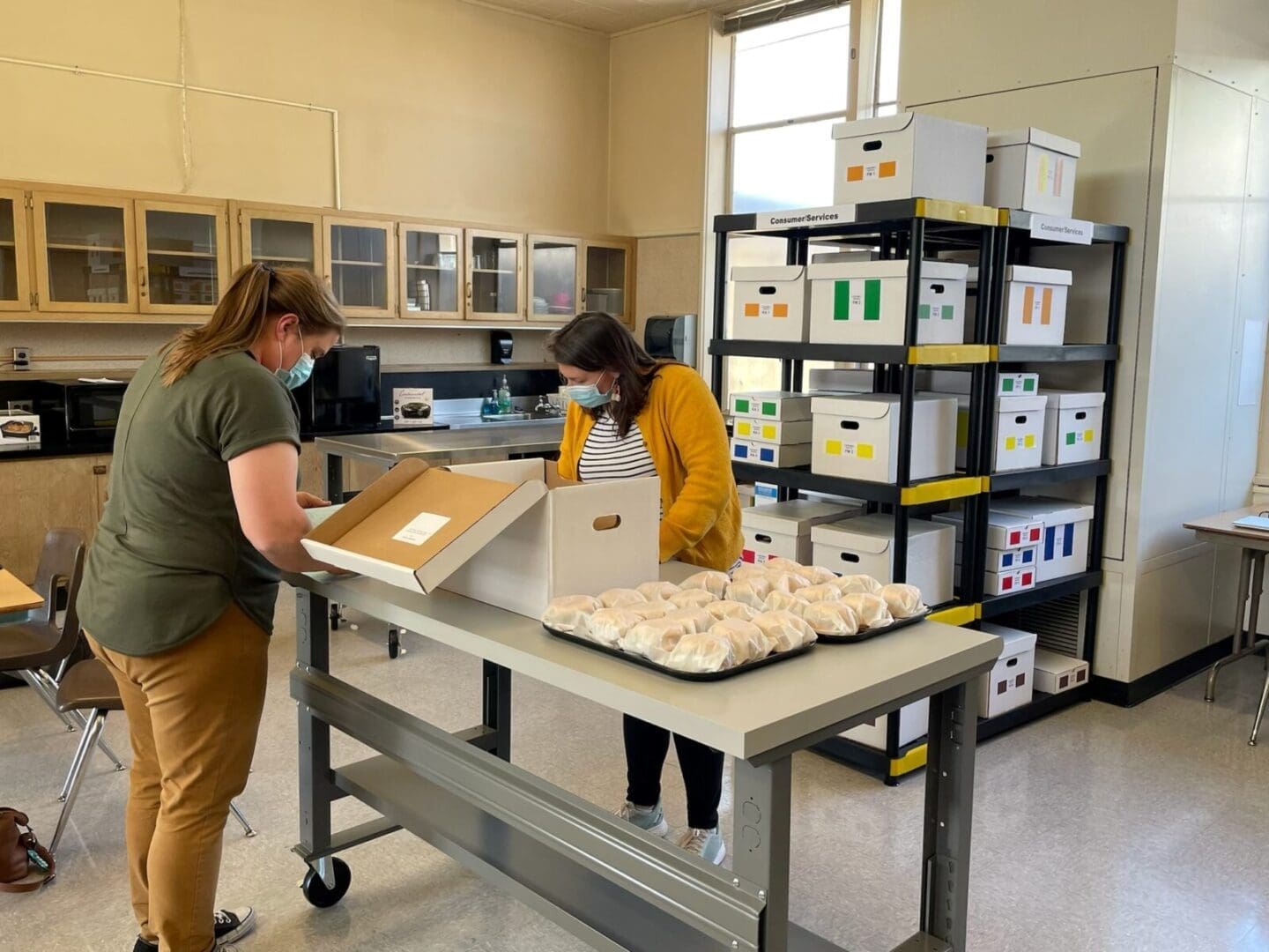 Staff packing boxed meals in storage room