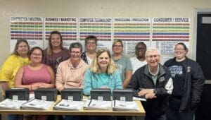 A group of people sitting at a table with laptops.