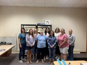 A group of people standing in front of a book case.