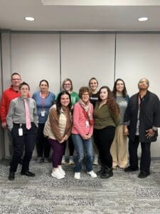 A group of people standing in front of some wall.