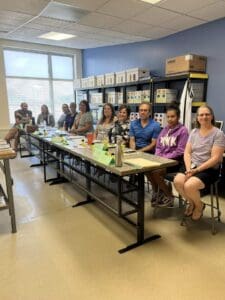 A group of people sitting at a table in front of boxes.