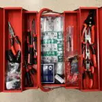 A red tool box with many different tools inside of it.