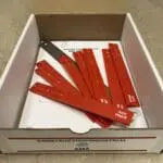 A box of red plastic spatulas in the middle of its packaging.