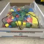 A box of colored blocks sitting on top of the floor.