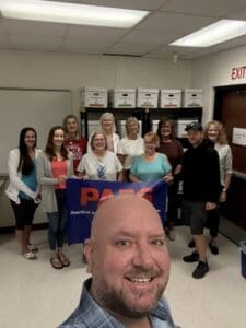 Group holding PAES banner in classroom.