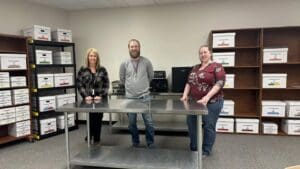 Three people standing in an organized office.