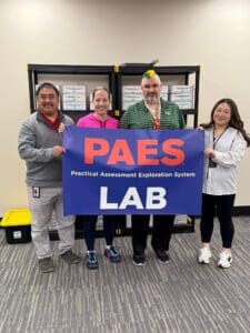 Four people holding PAES LAB sign.
