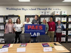 Group holding PAES LAB sign at school.