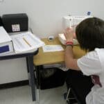 Student working at a sewing machine in work lab setting.